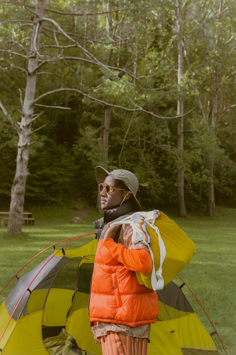 a person in an orange jacket standing next to a yellow tent